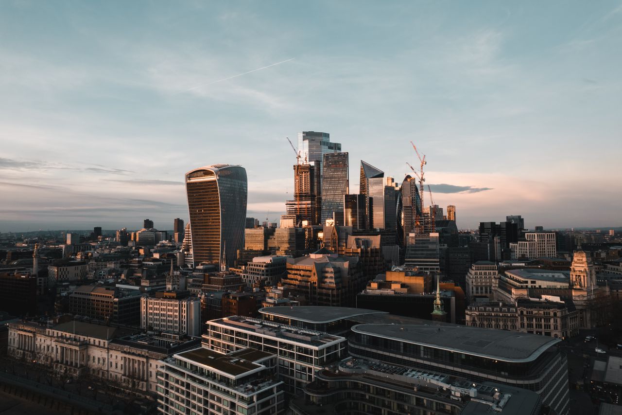 Breathtaking aerial view of London's modern skyline with iconic skyscrapers illuminated by the sunset.